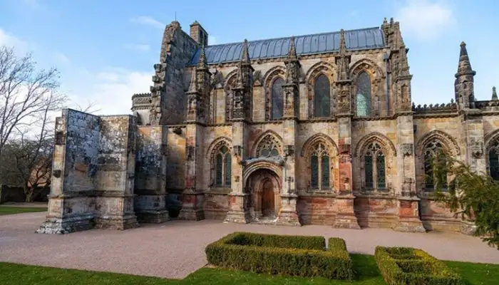 The ornate Gothic architecture and exterior stone carvings of Rosslyn Chapel in Midlothian, Scotland.