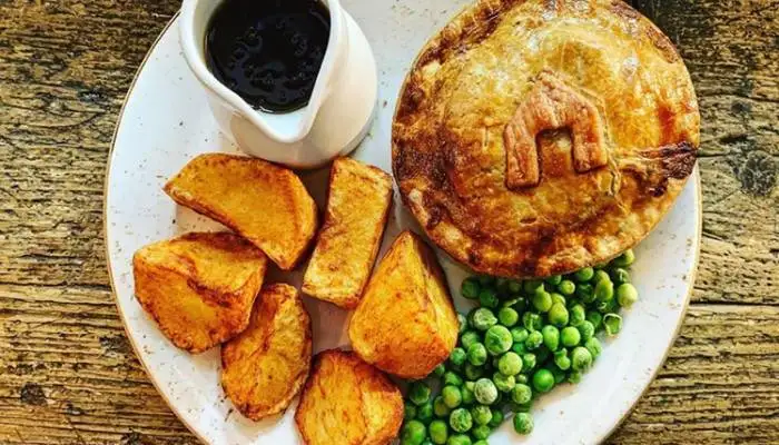 A cozy traditional British pub interior with a comforting pie, mash, and a pint of real ale.