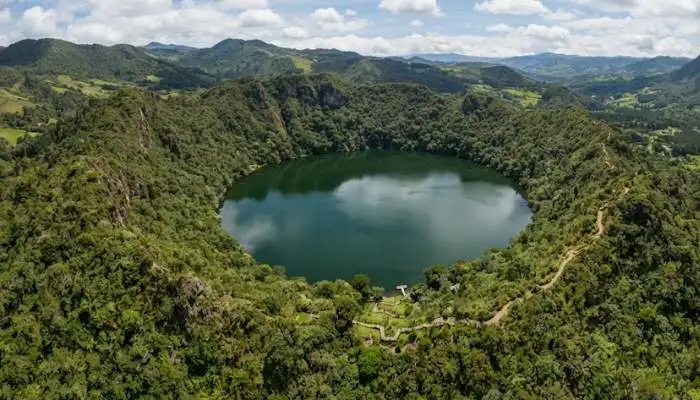 Aerial view of Lago Guatavita in Colombia, a lush green crater lake associated with the legend of El Dorado.